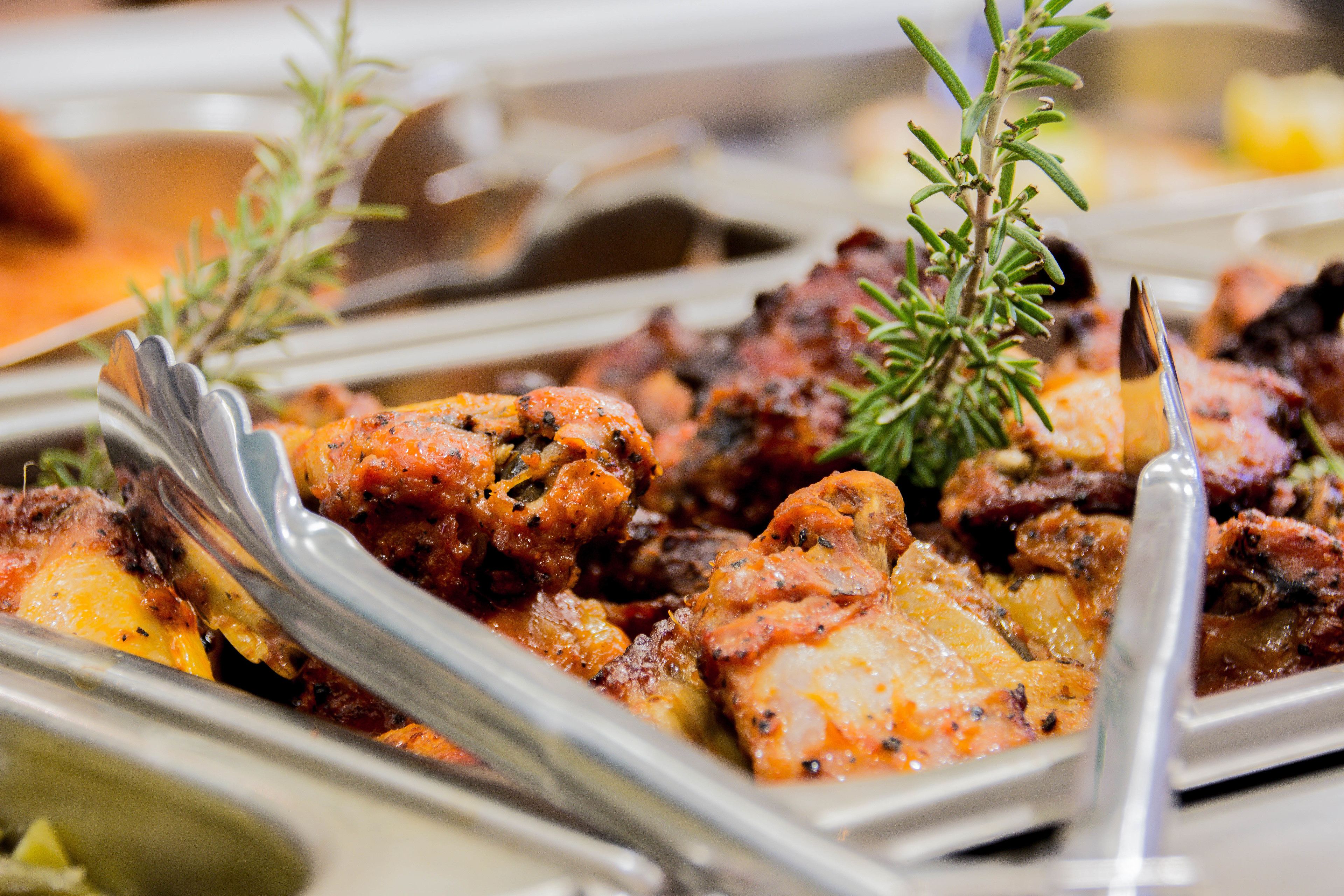 A buffet with various dishes, including roasted meats and vegetables, arranged on serving trays.