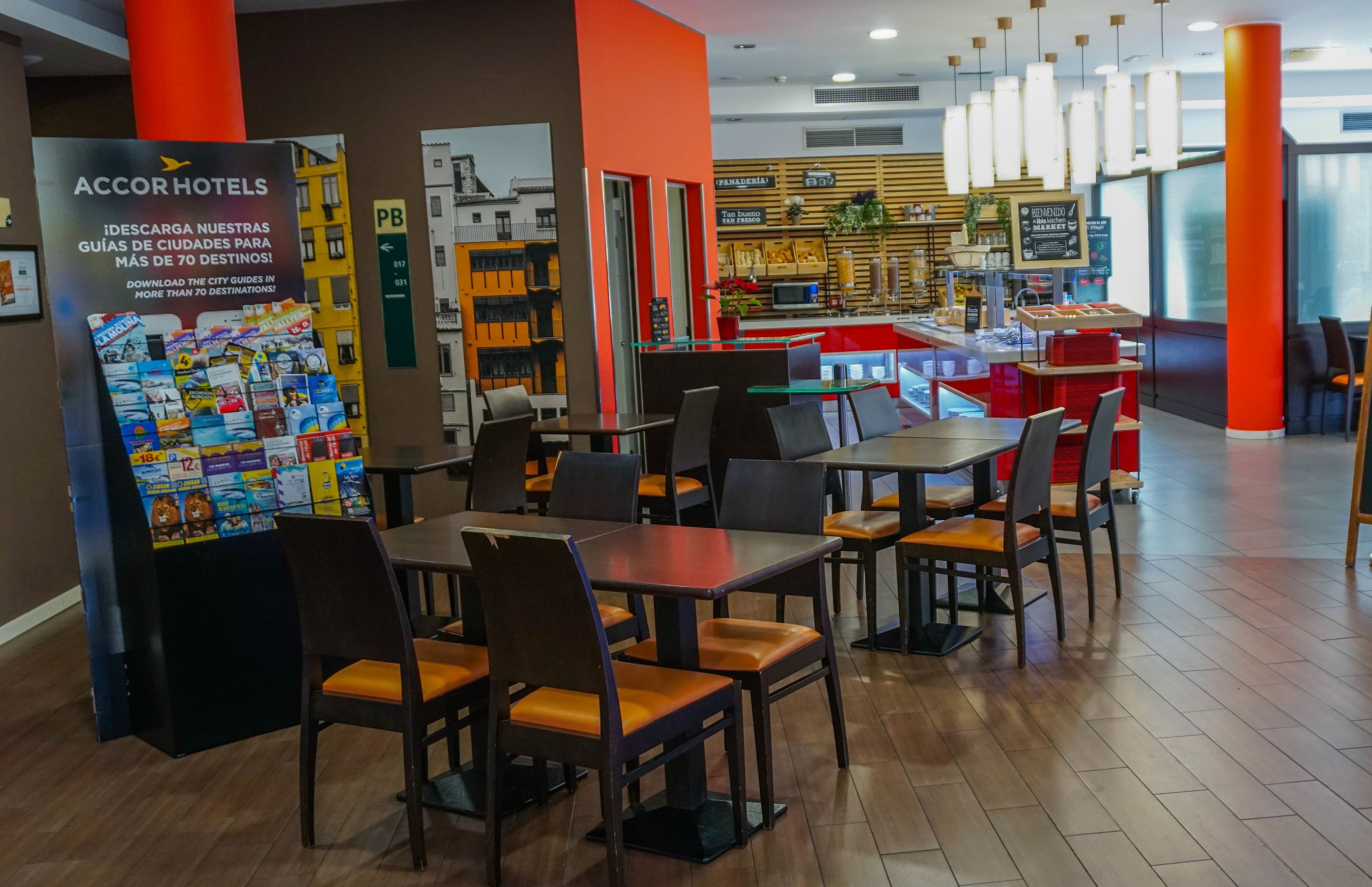 Un hall de hotel con mesas y sillas, un letrero PB y una barra con alimentos.