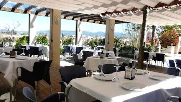 An outdoor dining area with tables set for two, covered by a pergola, and overlooking a scenic landscape. - El Tollo Hotel (Utiel)