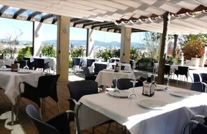 An outdoor dining area with tables set for two, covered by a pergola, and overlooking a scenic landscape. - El Tollo Hotel (Utiel)