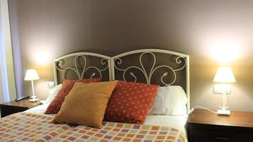 A neatly made bed with patterned bedding, two bedside lamps, and a wall-mounted nightstand.