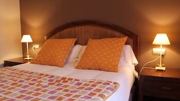 A neatly made bed with a patterned bedspread, two matching pillows, and two bedside lamps on wooden nightstands.