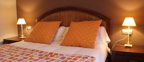 A neatly made bed with a patterned bedspread, two matching pillows, and two bedside lamps on wooden nightstands.