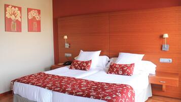 A neatly made bed with white and red bedding, a wooden headboard, and two bedside tables with lamps.