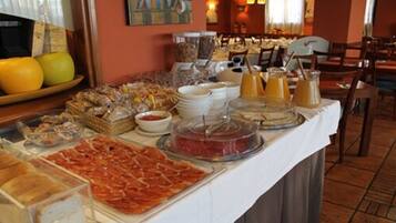 Una mesa de buffet con diversos alimentos, entre ellos carnes, quesos y frutas.