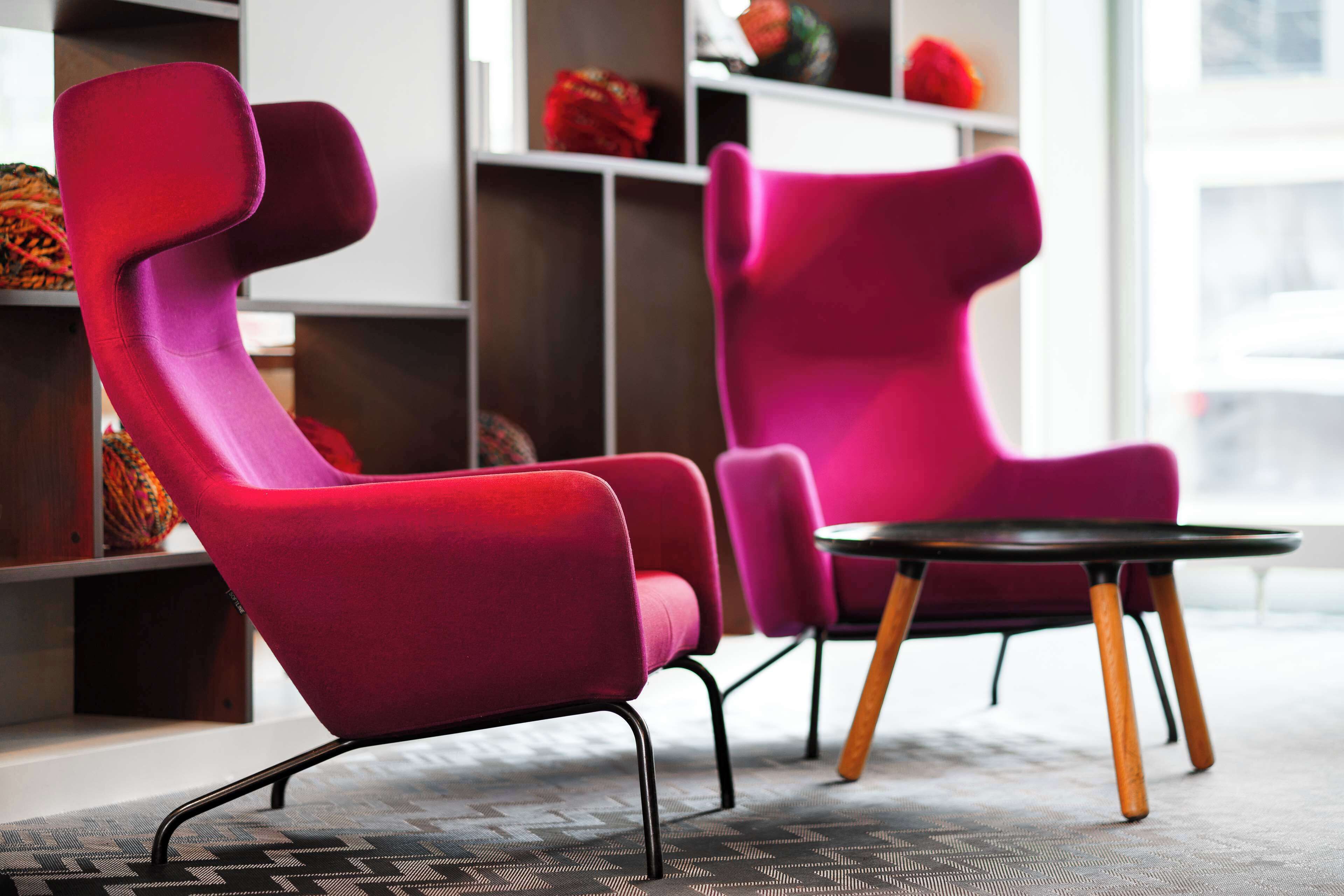 A modern interior with two vibrant red chairs and a small round table.