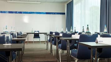 Un salón de conferencias con mesas, sillas y botellas de agua.