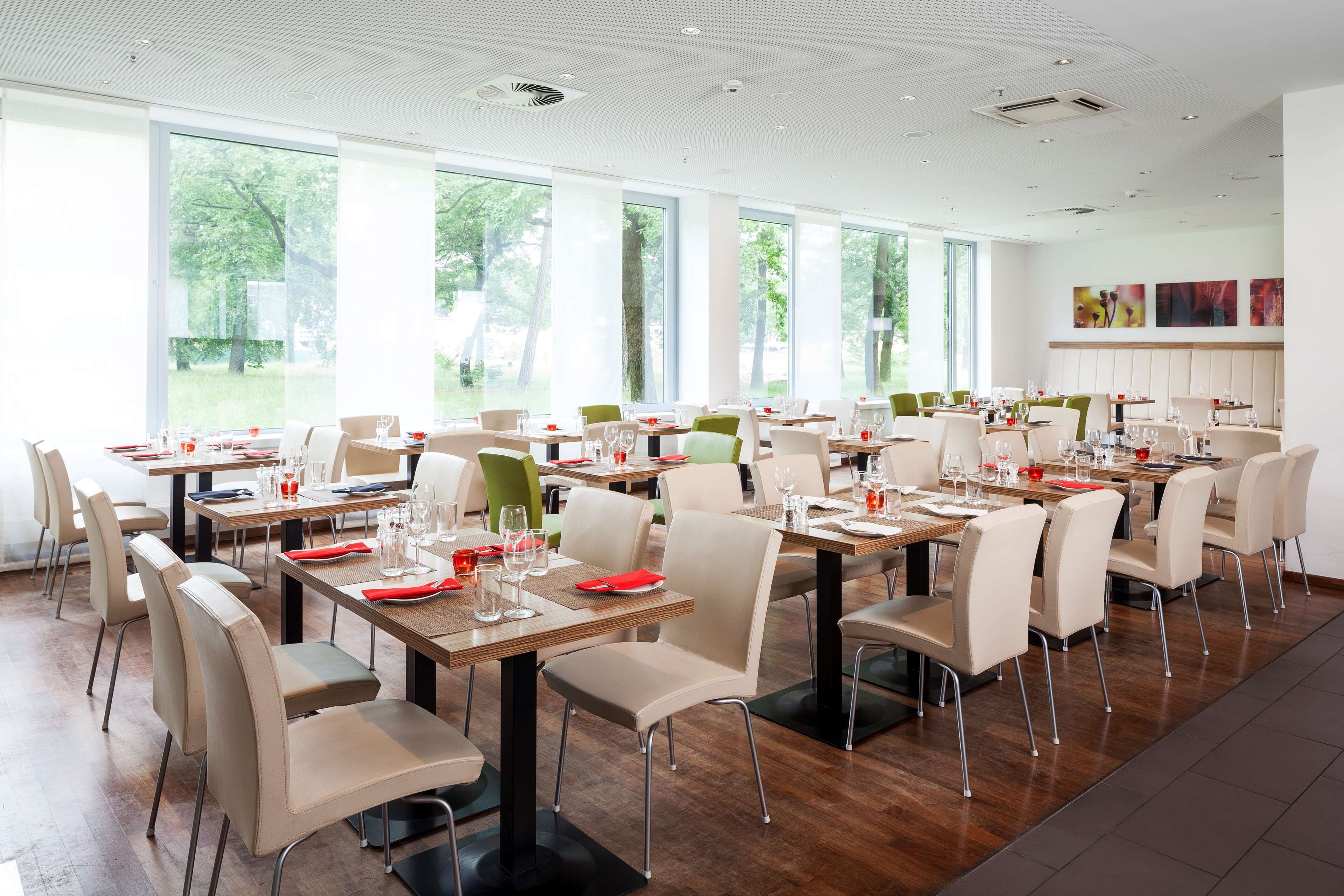 Un comedor amplio con varias mesas y sillas, ventanas grandes que ofrecen vistas al exterior y un diseño moderno de techo.
