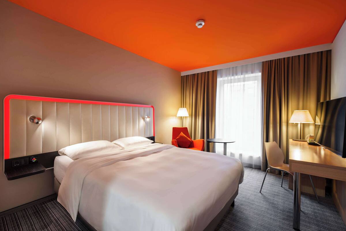 Een hotelkamer met een groot bed, een bureau en een stoel.