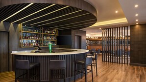 A modern bar area with a curved counter, multiple bar stools, and a well-stocked liquor shelf. - Four Points by Sheraton Lagos (Lagos)