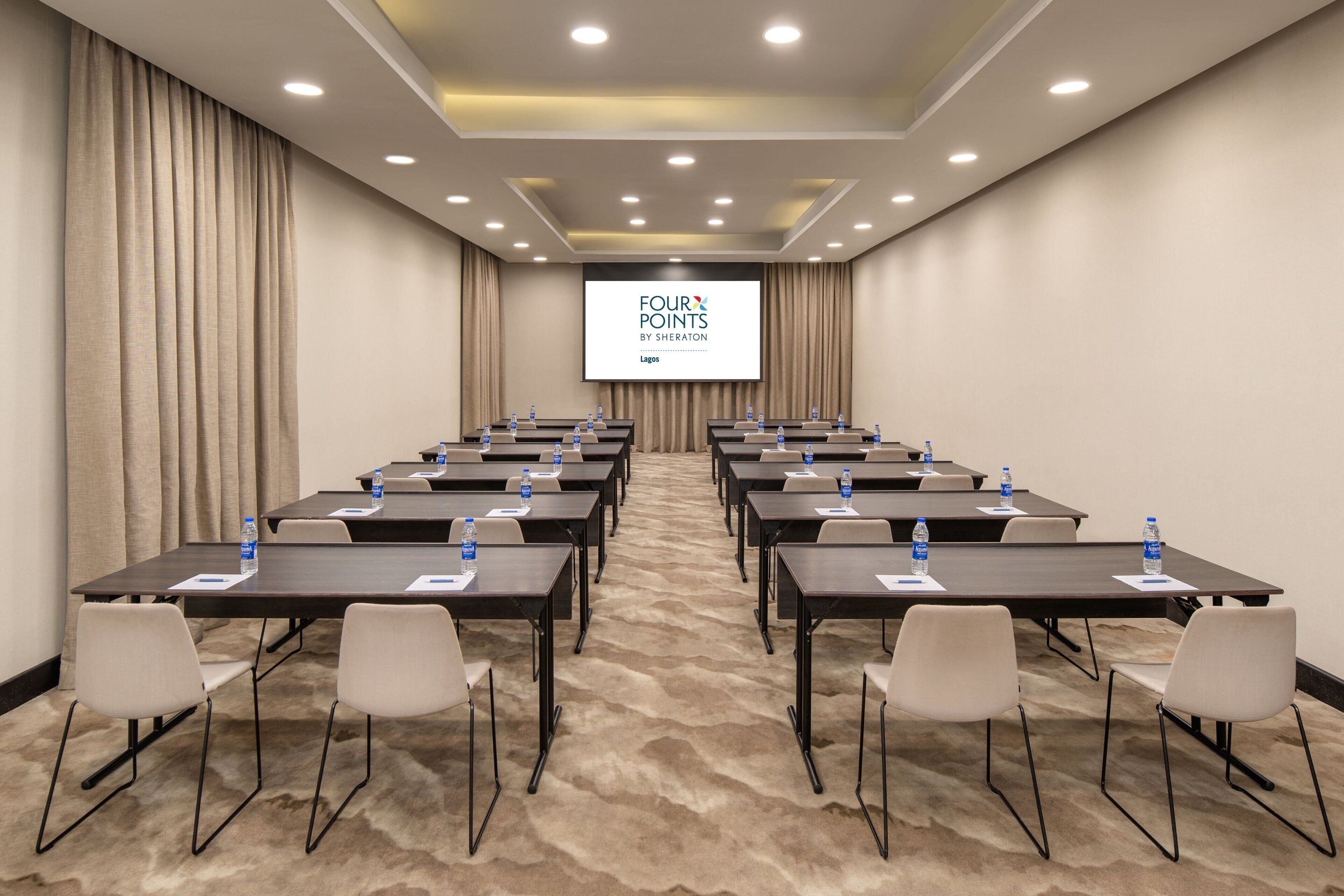 A conference room with a large screen displaying "FOUR POINTS BY SHERATON LAGOS".