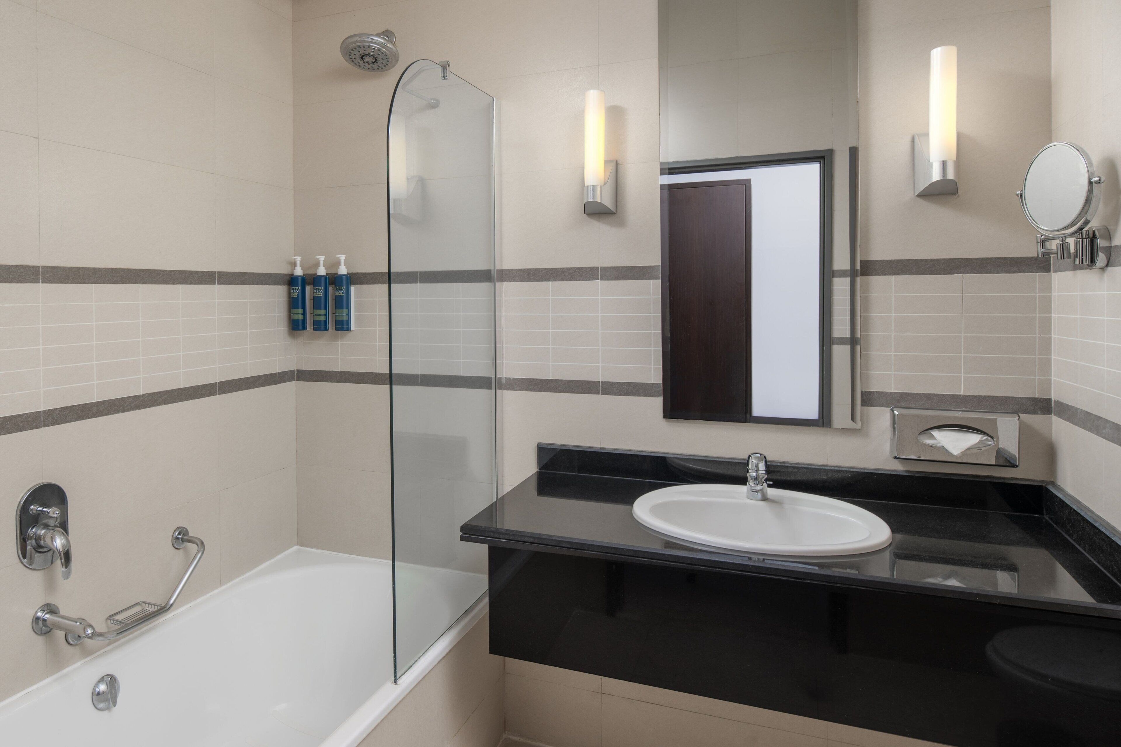 A modern bathroom with a glass shower enclosure, a black countertop sink, and a mirror.