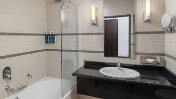 A modern bathroom with a glass shower enclosure, a black countertop sink, and a mirror.