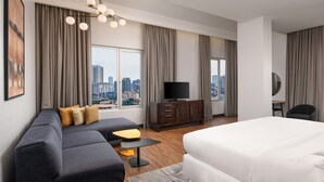 A modern hotel room with a large bed, a sofa, a small table, a TV, and a city view. - Four Points by Sheraton Lagos (Lagos)