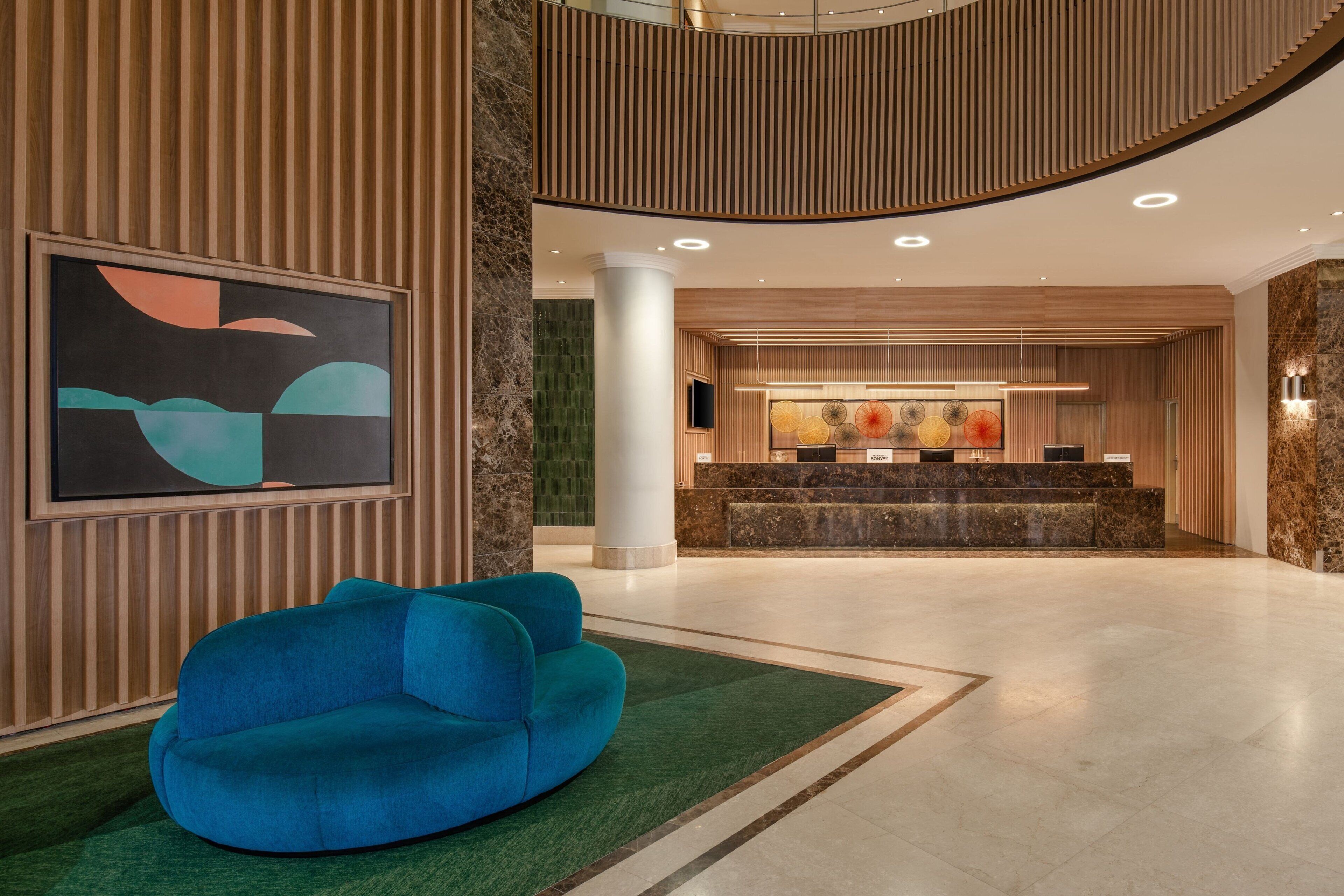 A modern lobby with a reception desk, a blue sofa, and abstract artwork on the wall.