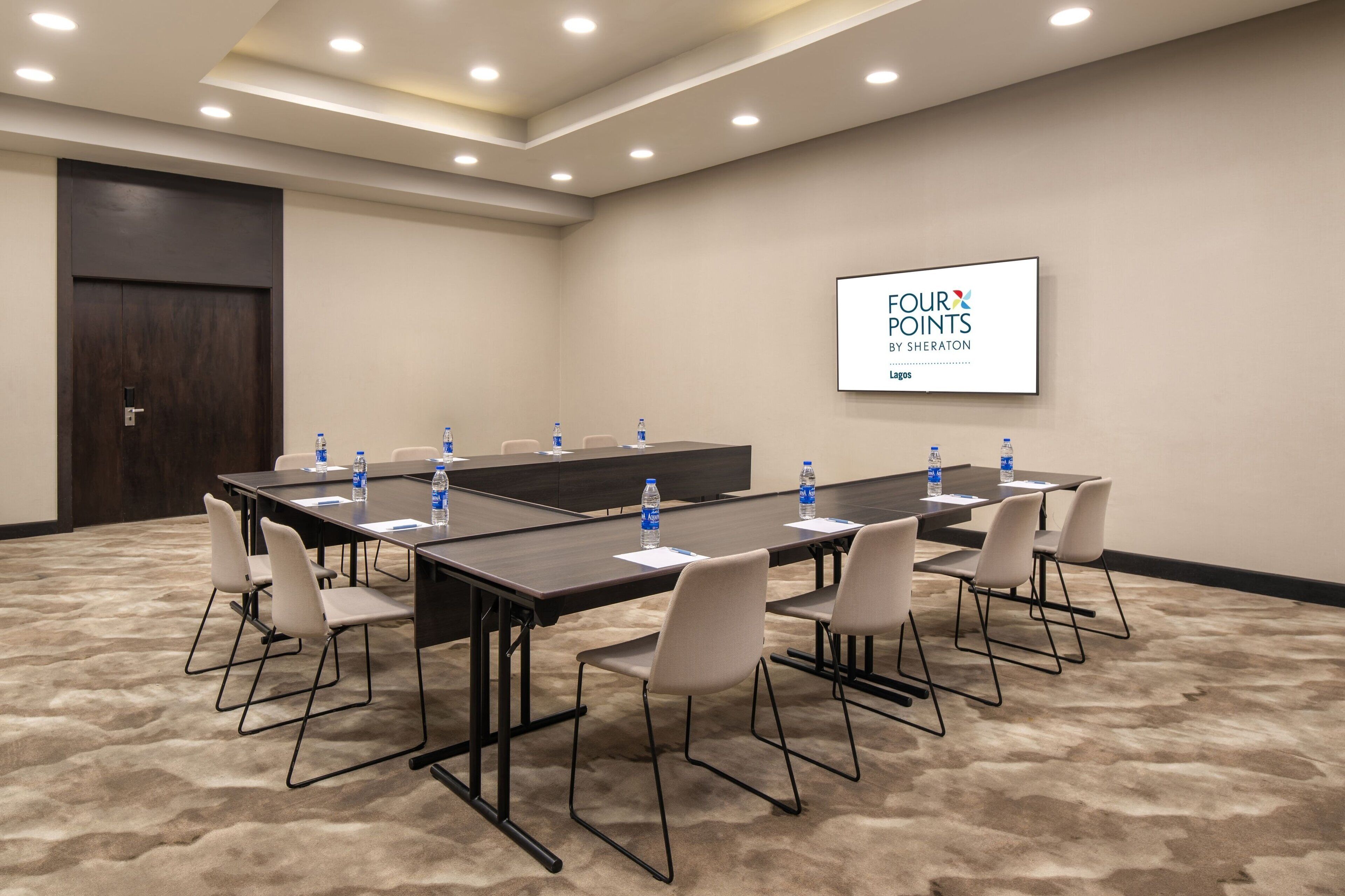 Ett konferensrum med ett långt bord, stolar och en skärm som visar texten ”FOUR POINTS BY SHERATON LAGOS”.