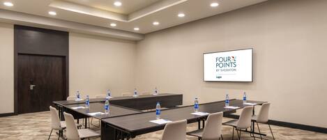 A conference room with a long table, chairs, and a screen displaying 'FOUR POINTS BY SHERATON LAGOS'.