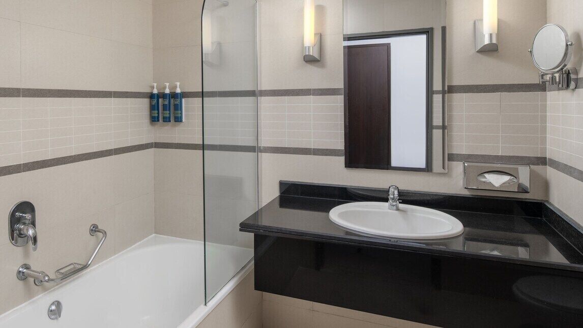 A modern bathroom with a glass-enclosed shower, a white sink, and a black countertop.