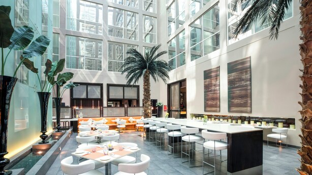 A spacious indoor area with high ceilings, large windows, and a central seating area with tables and chairs. - Centro Barsha (Dubai)