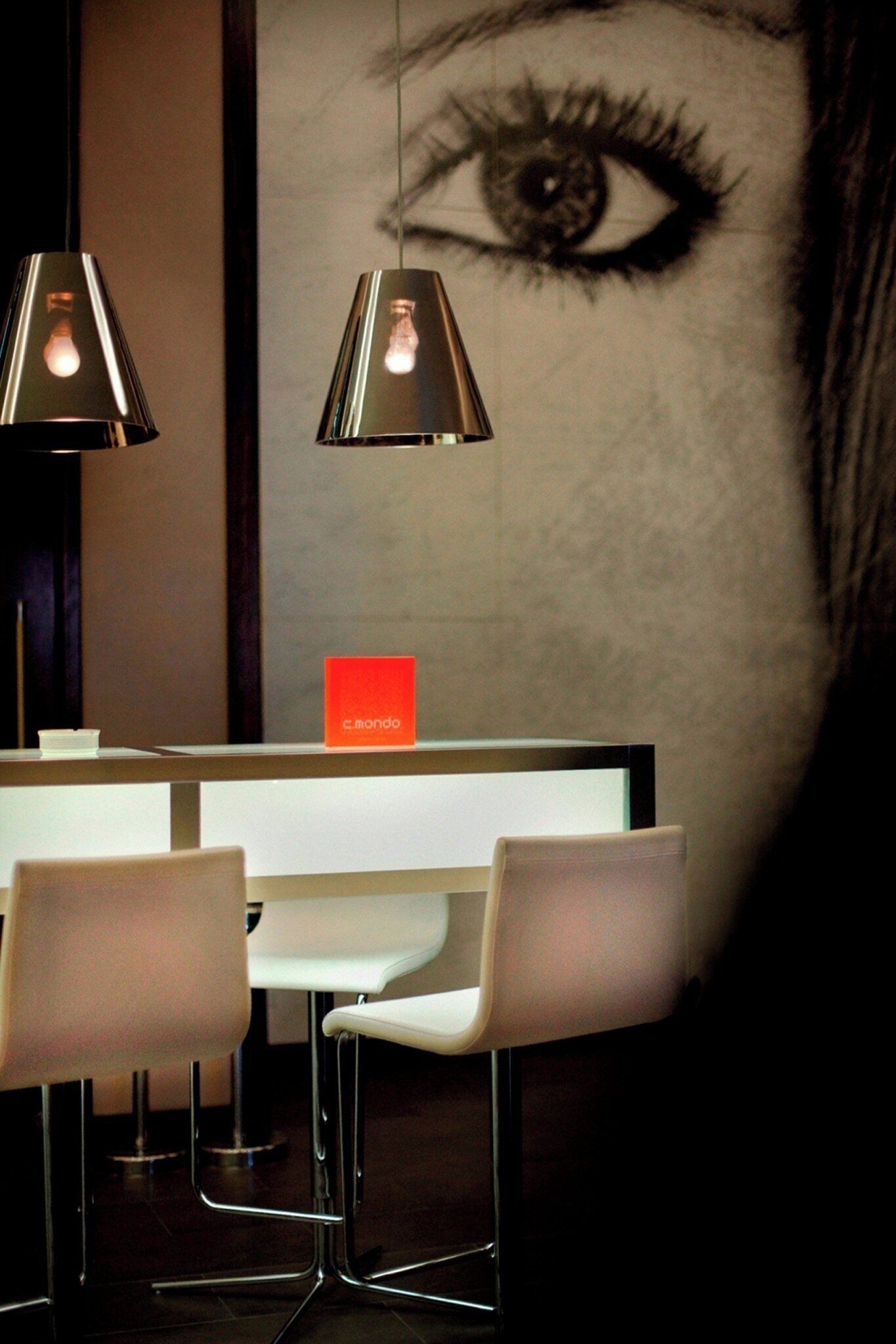 A modern bar area with two pendant lights, a white counter, and bar stools.