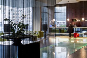 A modern lobby with a reception desk, seating area, and large windows. - Centro Barsha (Dubai)