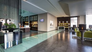 A modern lobby with a glass floor, seating area, and a reception desk. - Centro Barsha (Dubai)