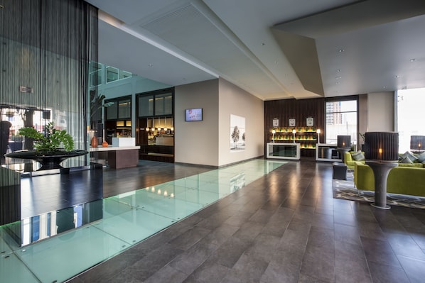 A modern lobby with a glass floor, seating area, and a reception desk. - Centro Barsha (Dubai)