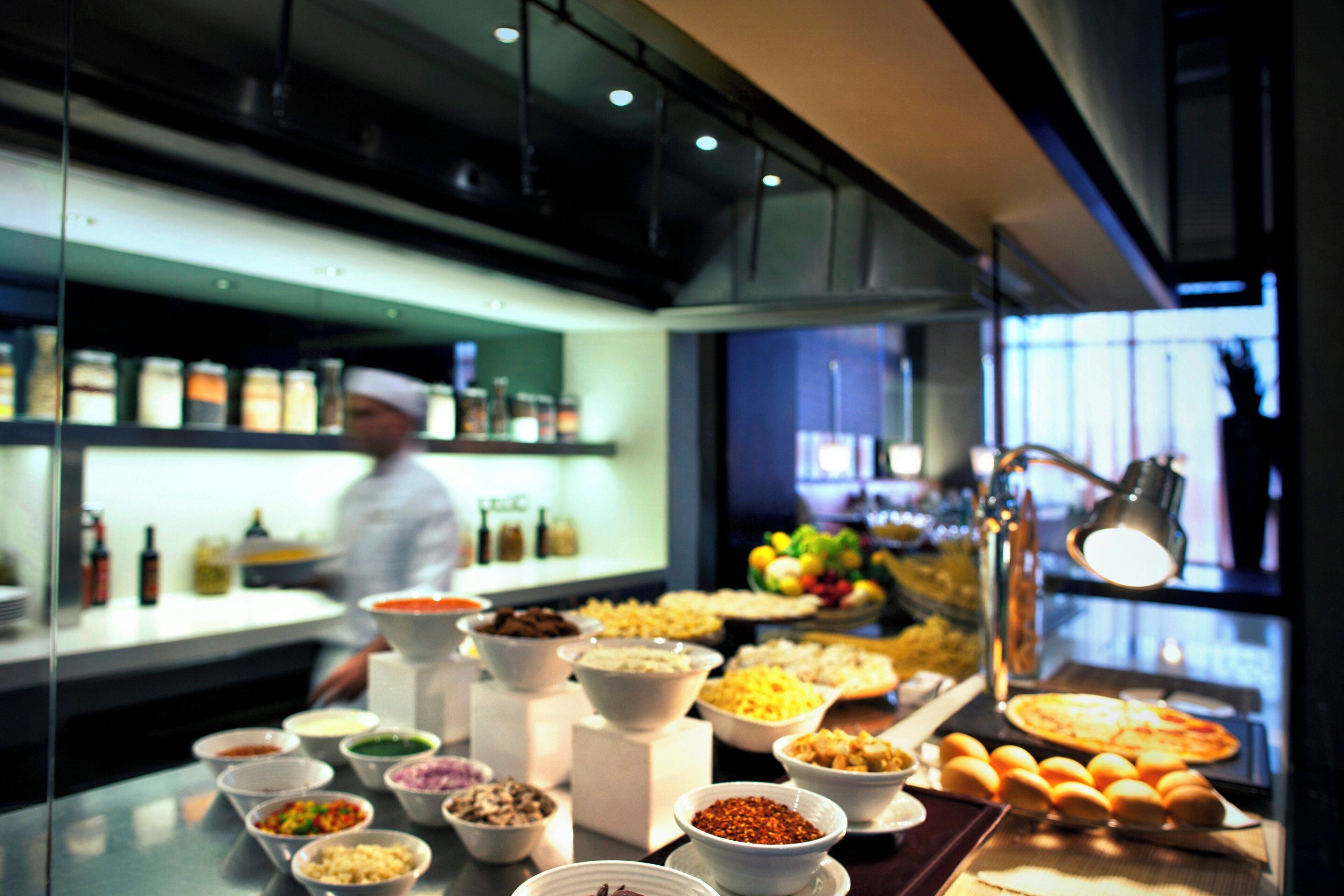 A buffet with various food items and a chef in the background.