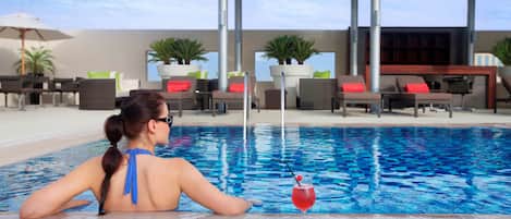 Una piscina al aire libre, sombrillas, sillones reclinables de piscina