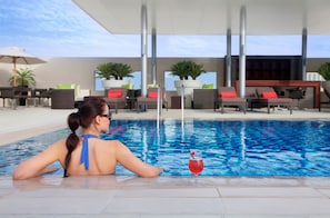 Uma área de piscina com espreguiçadeiras e guarda-sóis.