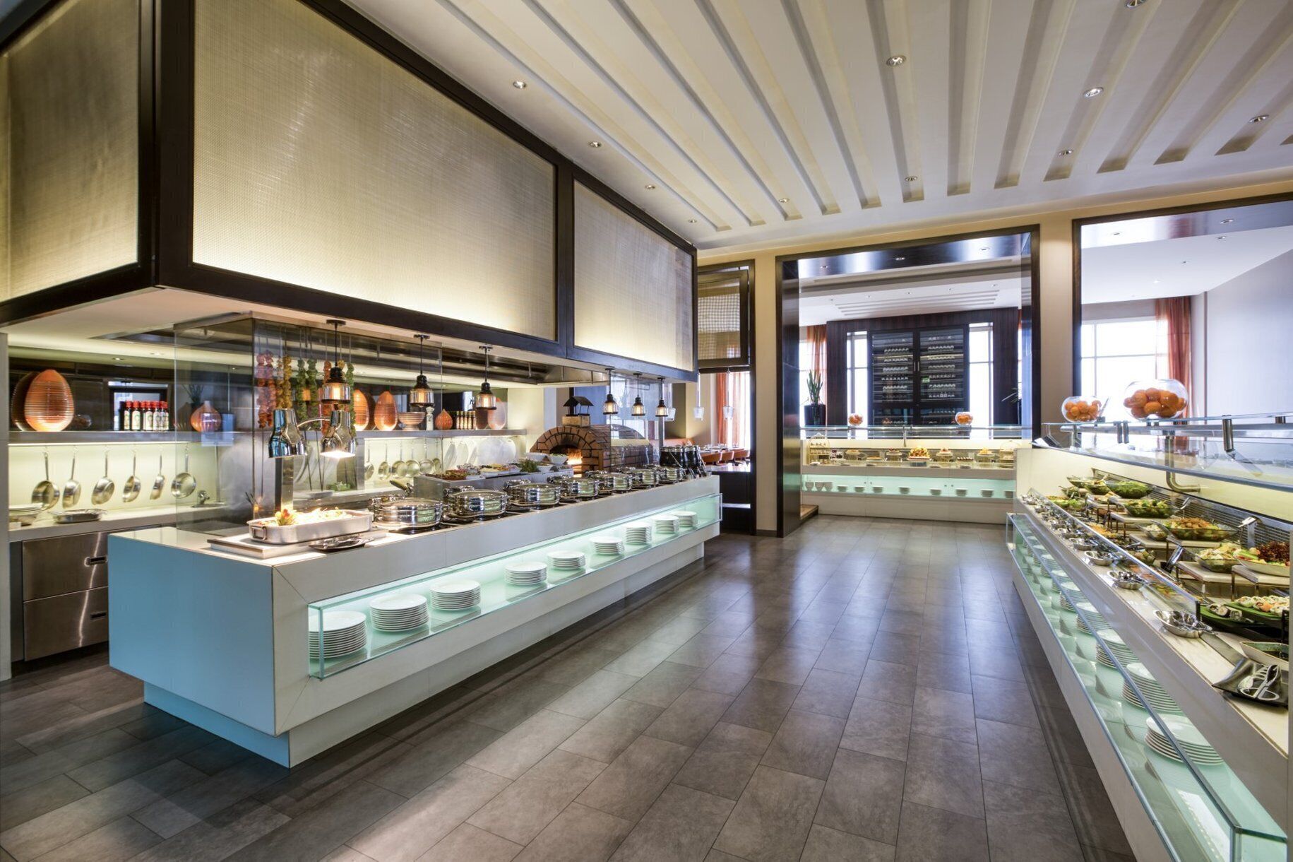 A modern buffet setup with a central serving area and multiple glass display cases.