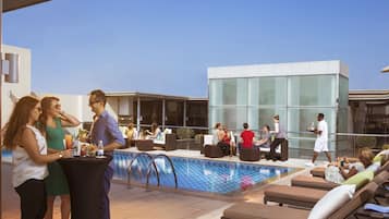 Una piscina al aire libre, sombrillas, sillones reclinables de piscina