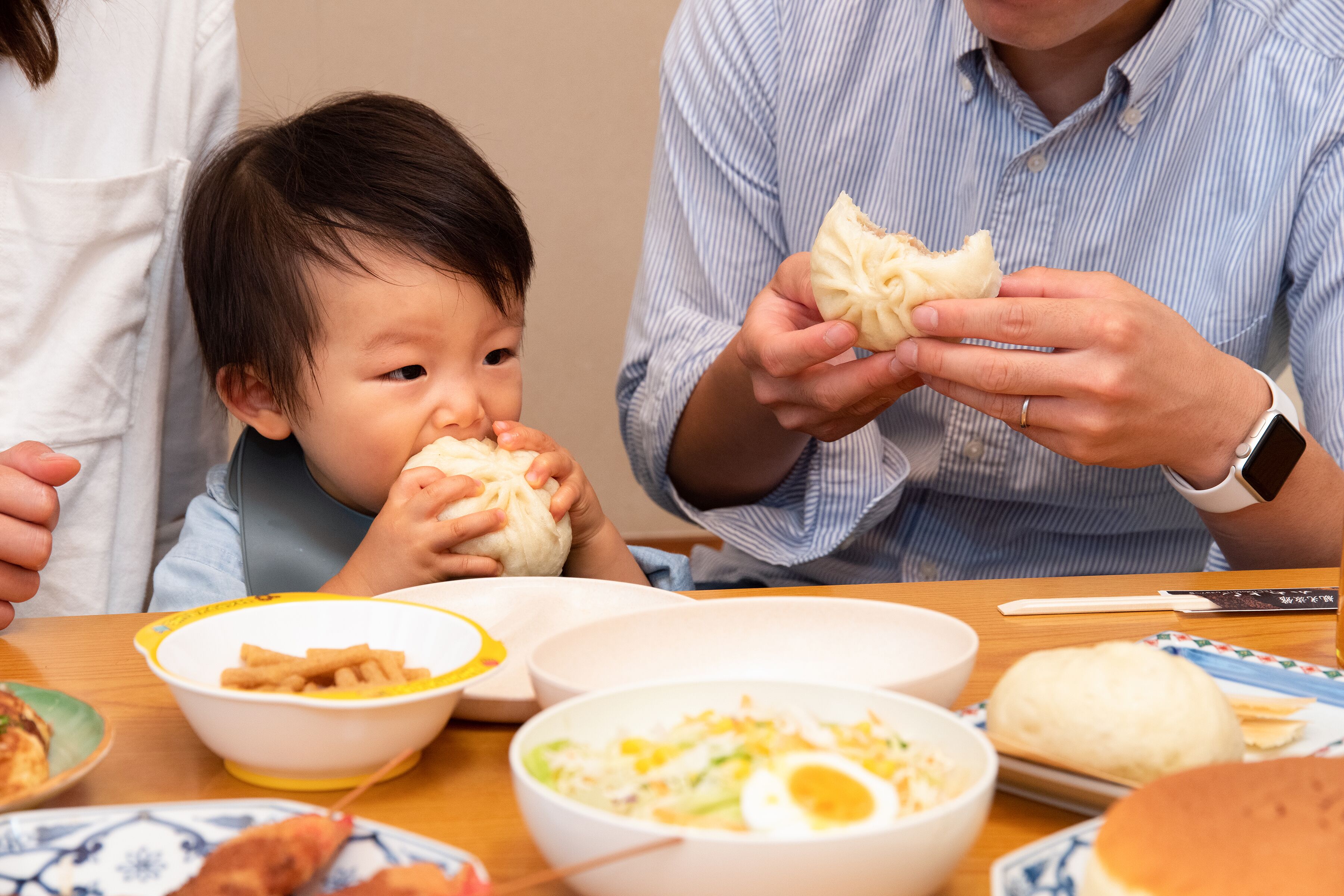 A dining table with various dishes including a bowl of soup, a plate with a boiled egg, and a plate with a piece of bread.