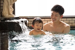 A man and a child in a swimming pool with a water feature. - Kaneyoshi Ryokan (Osaka)