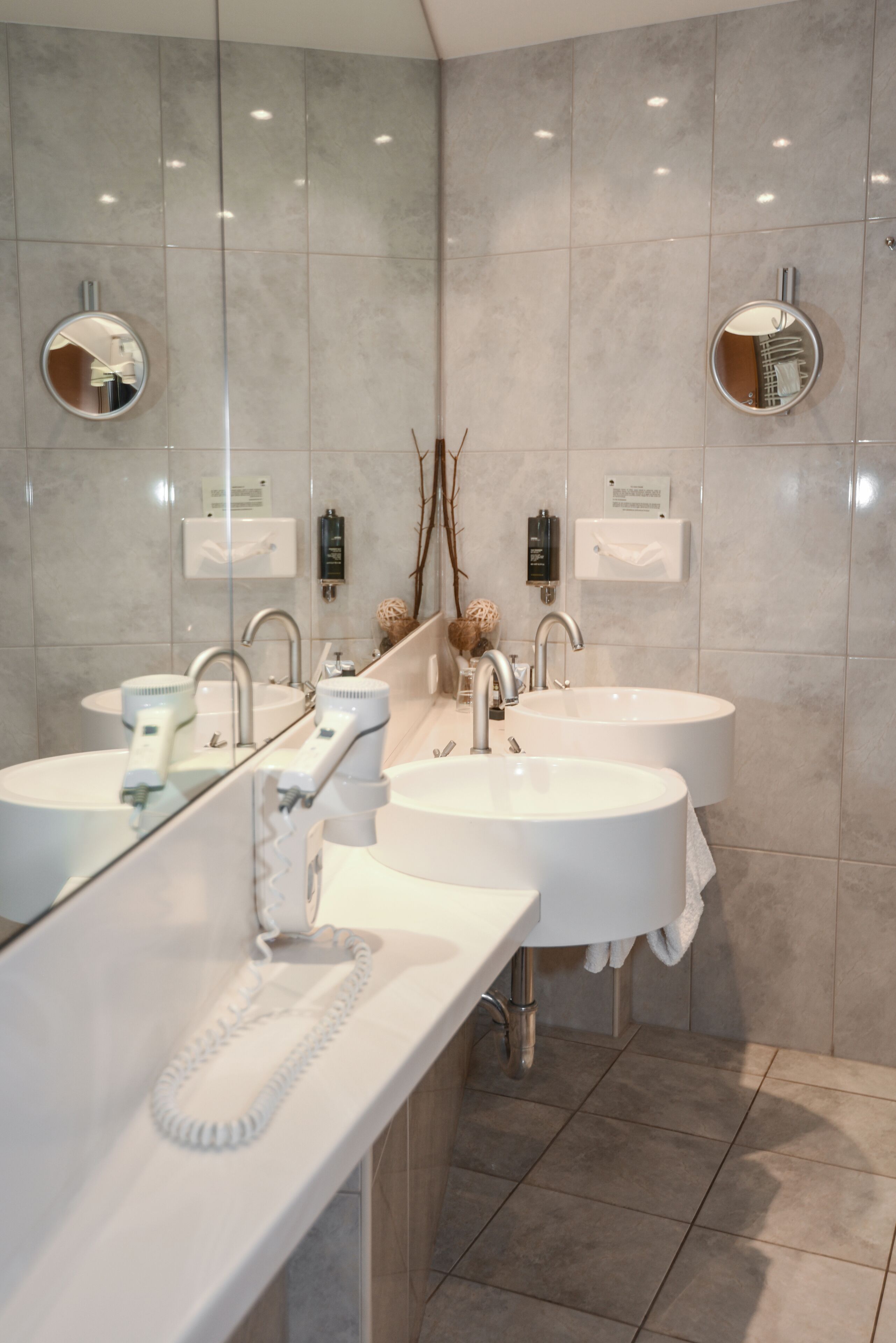 Une salle de bain moderne avec deux lavabos, un miroir et un porte-serviettes.
