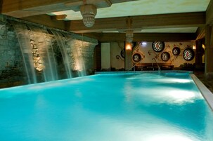 Ein großes Hallenbad mit Steinwand und Wasserfall.