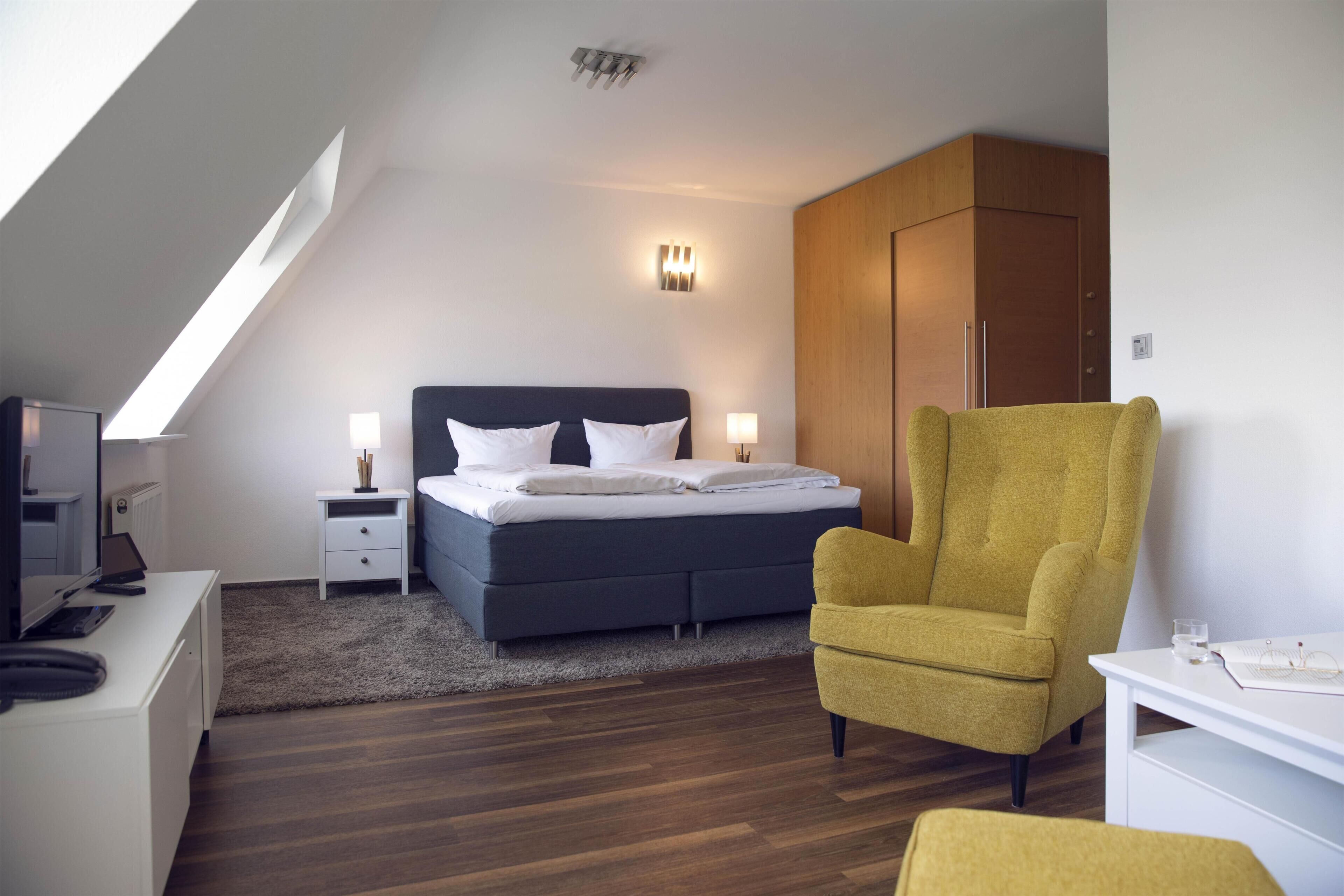 Une chambre à coucher moderne, comprenant un lit, des tables de chevet, un bureau, une chaise et une armoire.