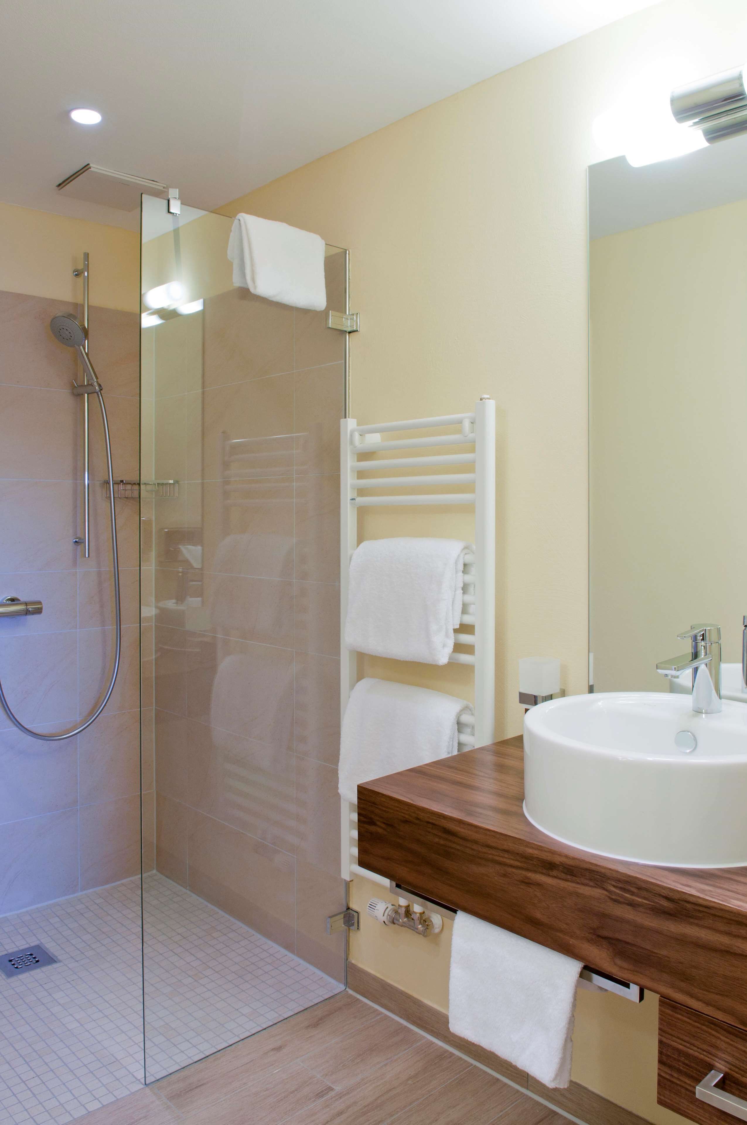 Une salle de bain moderne avec une douche à parois de verre, un meuble-lavabo en bois et un porte-serviettes.