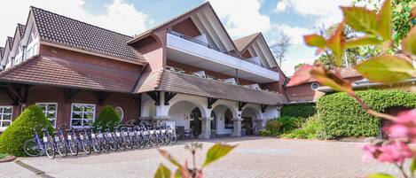 A building with a tiled roof, a covered entrance, and a row of bicycles parked outside.