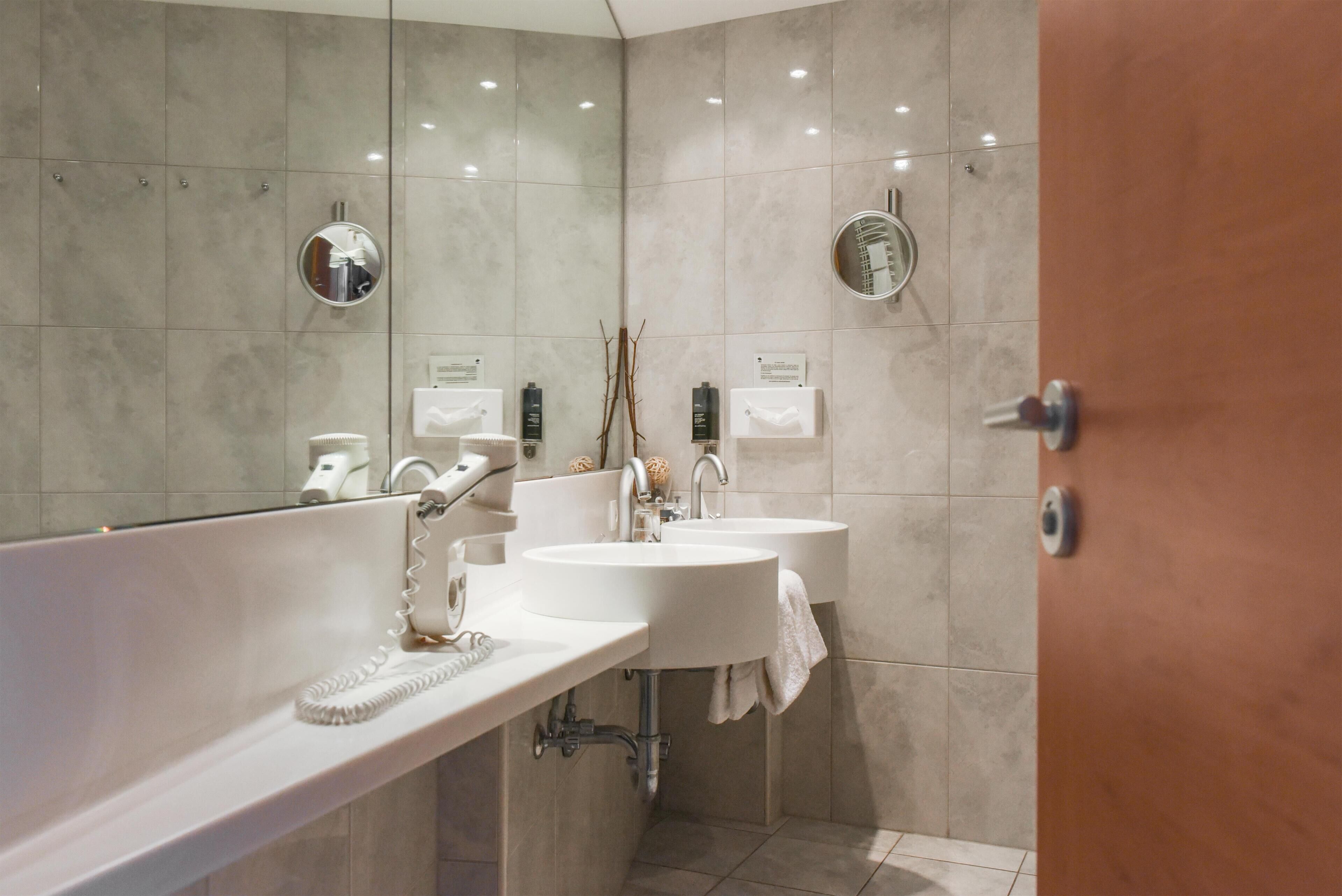 Une salle de bain moderne avec deux lavabos, un miroir et un porte-serviettes.