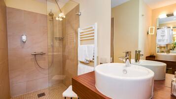 Une salle de bain moderne avec une douche à parois de verre, un meuble-lavabo en bois doté de deux vasques et un porte-serviettes blanc.