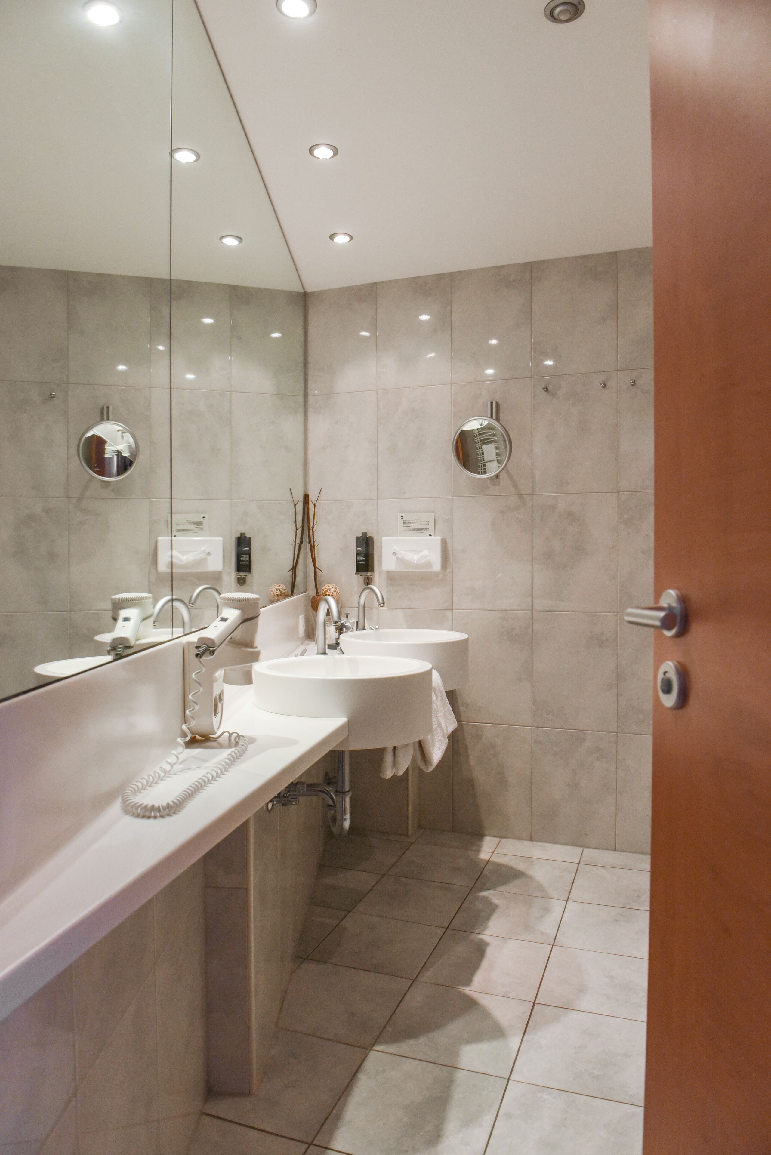 Ein modernes Badezimmer mit zwei Waschbecken, einem großen Spiegel und Einbauleuchten.