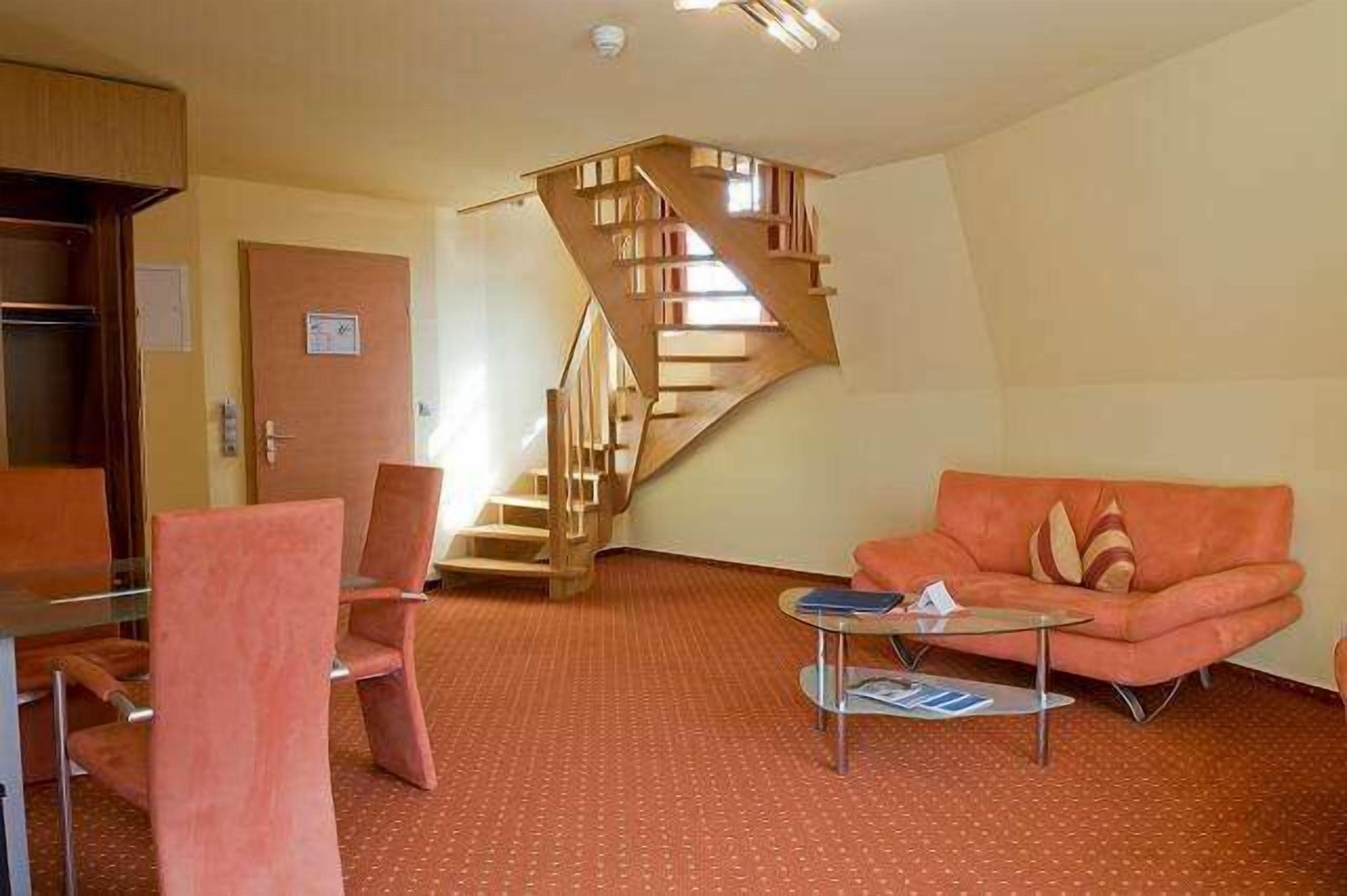 A modern living room with a spiral staircase, a glass coffee table, and a sofa with a cushion.