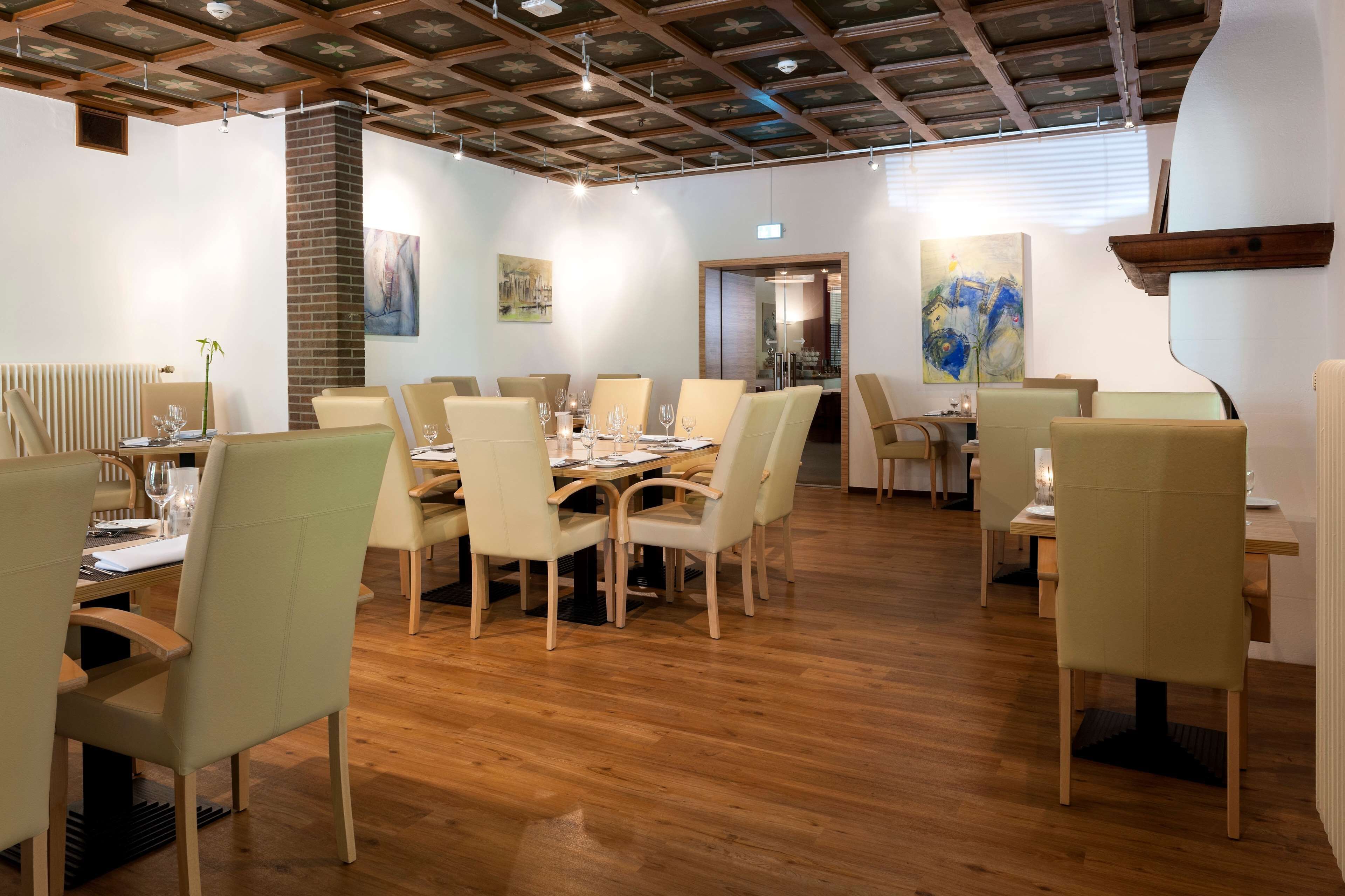 A dining area with wooden tables and chairs, a brick wall, and artwork on the walls.