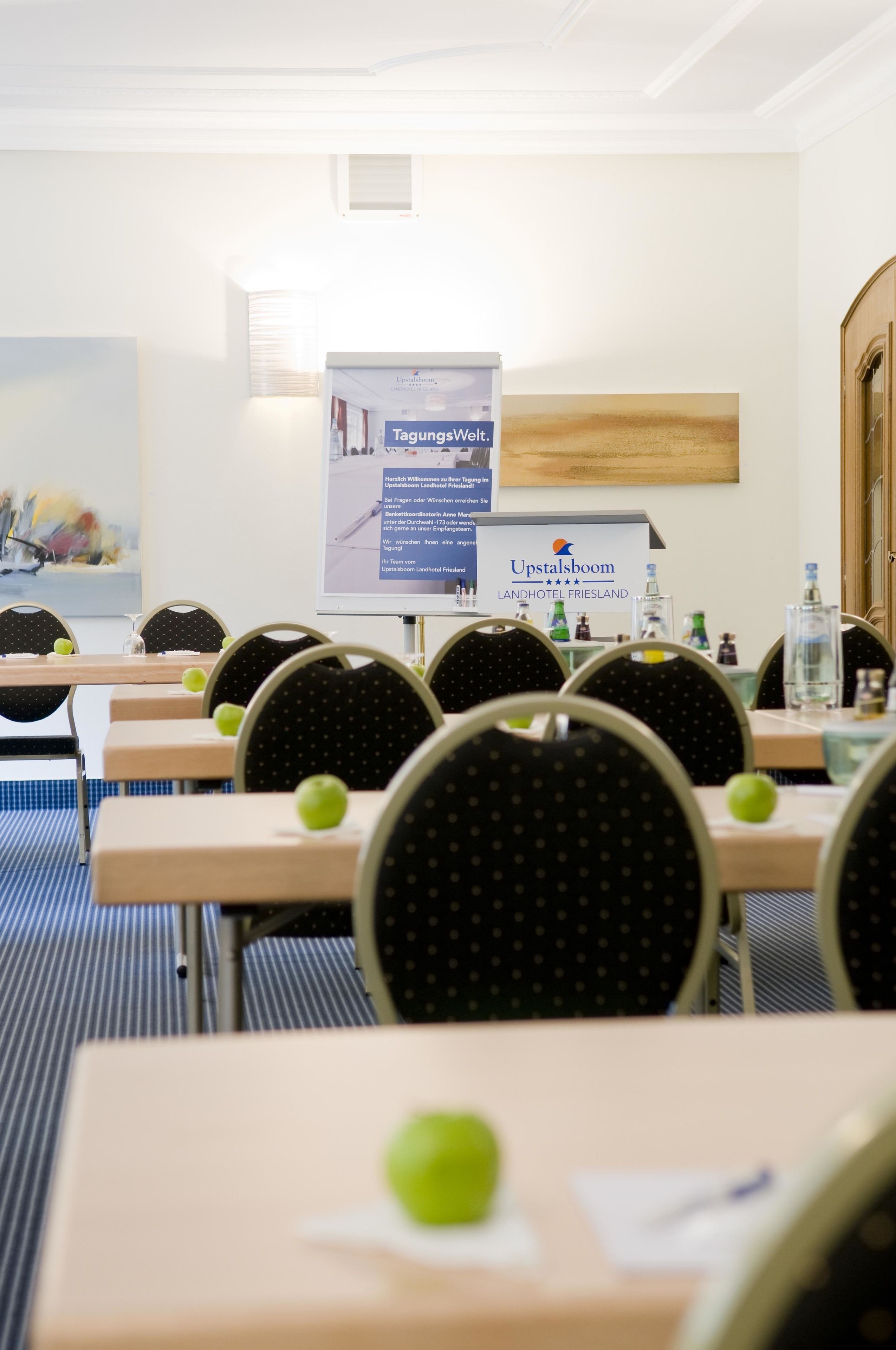 Une salle de conférence avec des tables et des chaises, une banderole et un tableau accroché au mur.