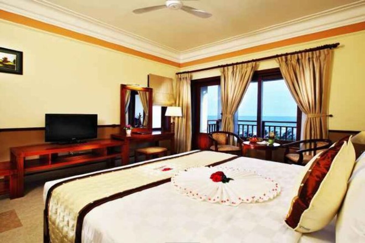 A hotel room with a bed, a television, a desk, and a view of the outdoors.