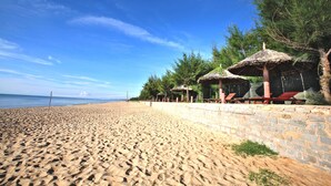 Privat strand, hvit sand, solsenger og parasoller