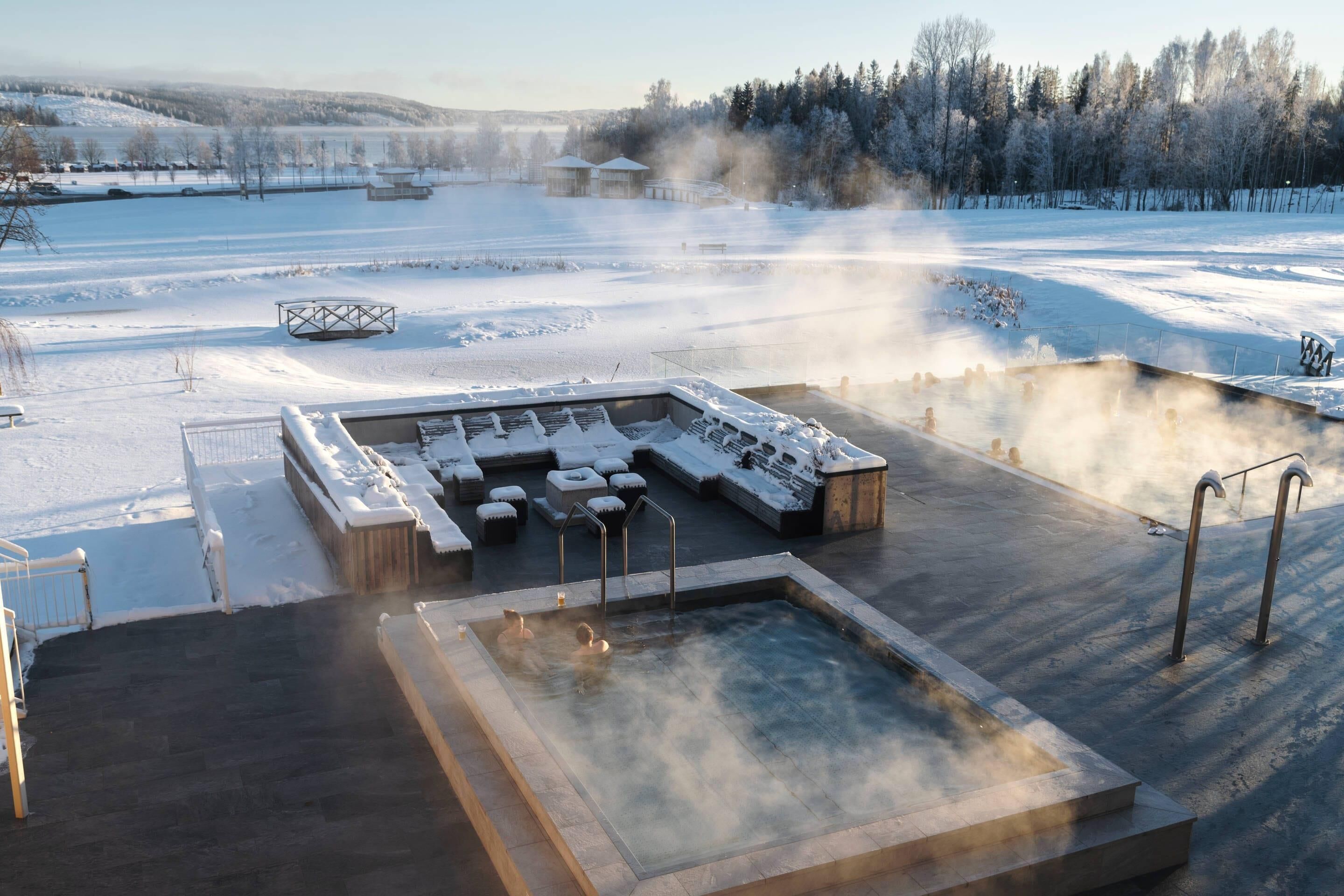 A hot spring area with a pool and seating, surrounded by a snowy landscape.