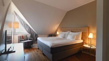 A modern bedroom with a large bed, a desk, and a chair.