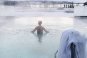 Una persona en una piscina amplia y transparente con vistas a un paisaje nevado al fondo.